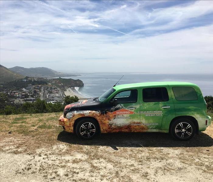 a green car with the ocean in the background