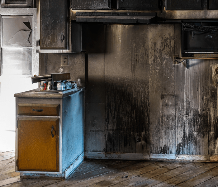 Kitchen cabinets, floor, and walls filled with black soot 